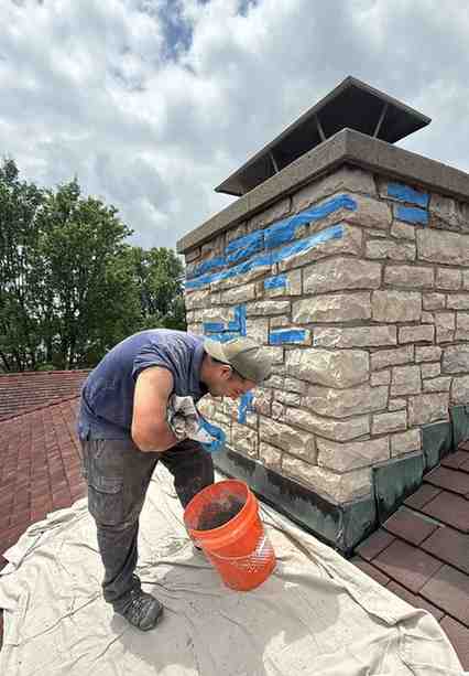 ChimCrew technician tuckpointing and repairing a stone chimney